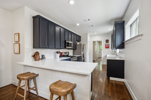 kitchen featuring visible vents, tasteful backsplash, a sink, a peninsula, and stainless steel appliances