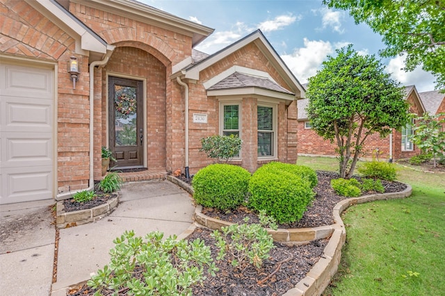 doorway to property featuring brick siding and a lawn