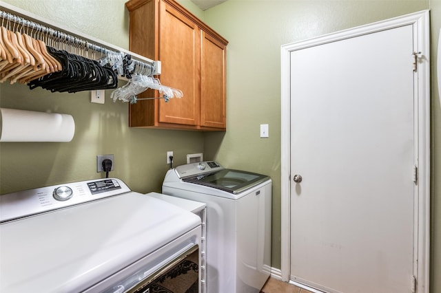 laundry area with a textured wall, cabinet space, and washer and clothes dryer