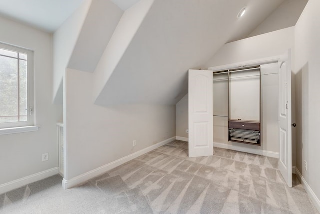 unfurnished bedroom with light colored carpet, baseboards, and vaulted ceiling