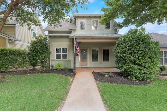 traditional home with a shingled roof, a porch, and a front lawn