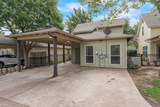 back of property with fence, central AC unit, a shingled roof, driveway, and a carport
