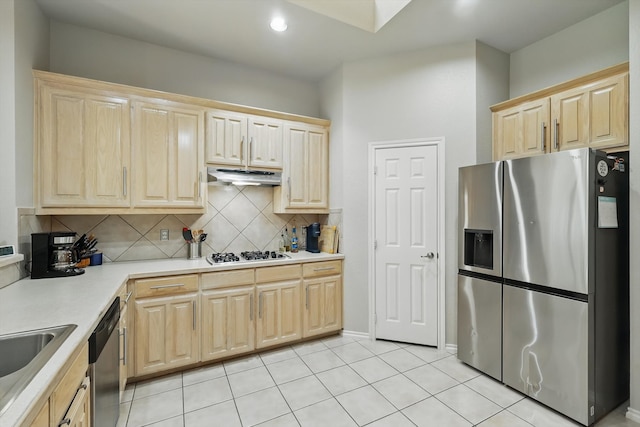 kitchen featuring decorative backsplash, light brown cabinetry, light countertops, under cabinet range hood, and stainless steel appliances