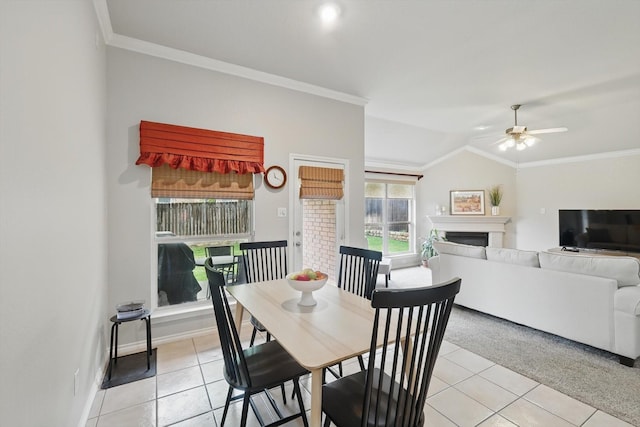 dining area featuring crown molding, light tile patterned flooring, a fireplace, baseboards, and a ceiling fan