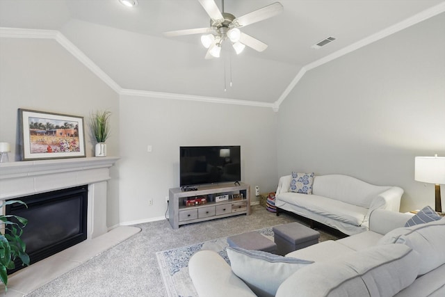 carpeted living room featuring a ceiling fan, visible vents, lofted ceiling, a glass covered fireplace, and ornamental molding