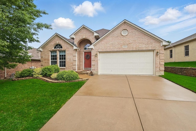 view of front of house featuring brick siding, an attached garage, driveway, and a front yard