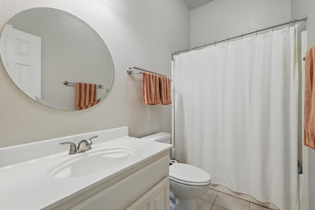 bathroom featuring toilet, a textured wall, tile patterned flooring, and vanity