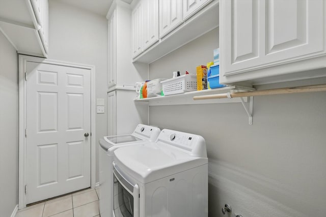 clothes washing area with light tile patterned floors, cabinet space, and washing machine and clothes dryer