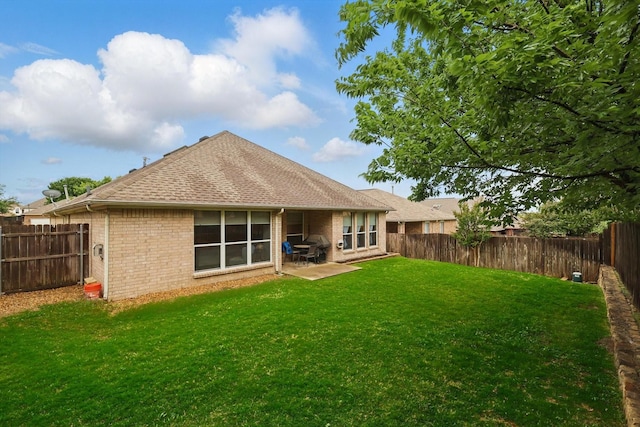 back of house featuring brick siding, a fenced backyard, and a lawn