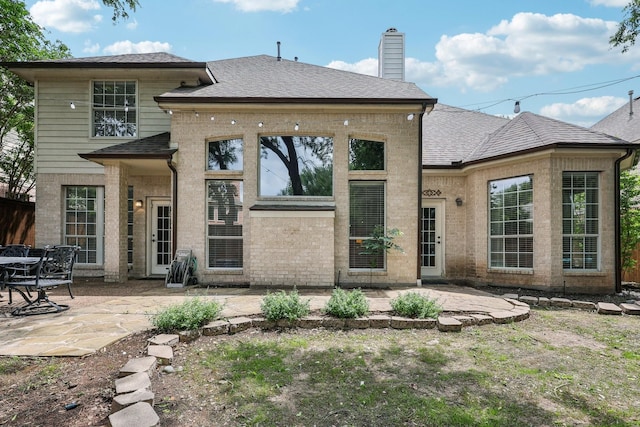 rear view of property featuring a shingled roof, a chimney, and a patio area