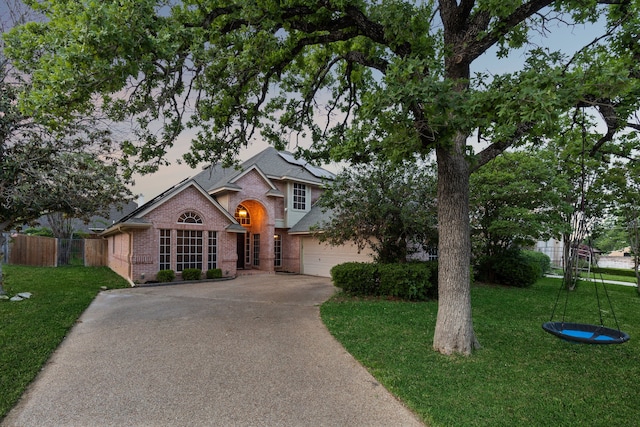 view of front of home with concrete driveway, brick siding, solar panels, and a front yard