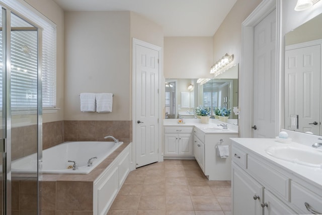 full bath featuring two vanities, tile patterned floors, a tub with jets, and a sink