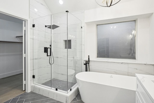 bathroom with recessed lighting, a marble finish shower, a freestanding bath, and vanity