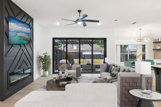 living area with visible vents, ceiling fan with notable chandelier, and light wood-style floors