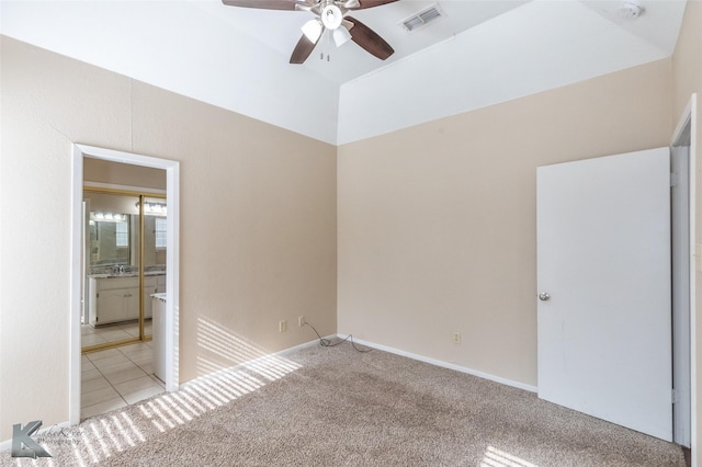 unfurnished bedroom with visible vents, carpet floors, tile patterned flooring, ensuite bathroom, and ceiling fan