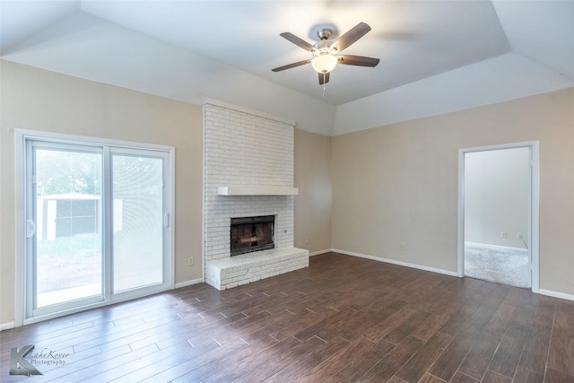unfurnished living room with a fireplace, ceiling fan, vaulted ceiling, and dark wood-type flooring