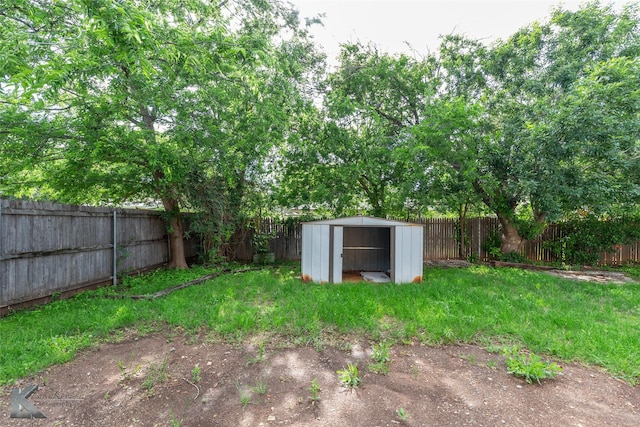 view of yard with an outdoor structure, a fenced backyard, and a shed