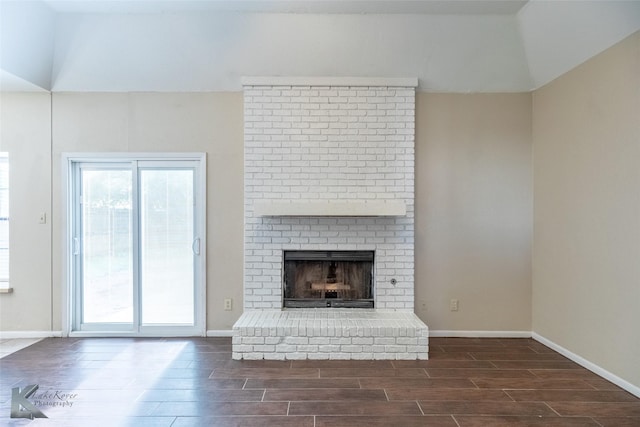 unfurnished living room featuring baseboards, wood tiled floor, and a brick fireplace