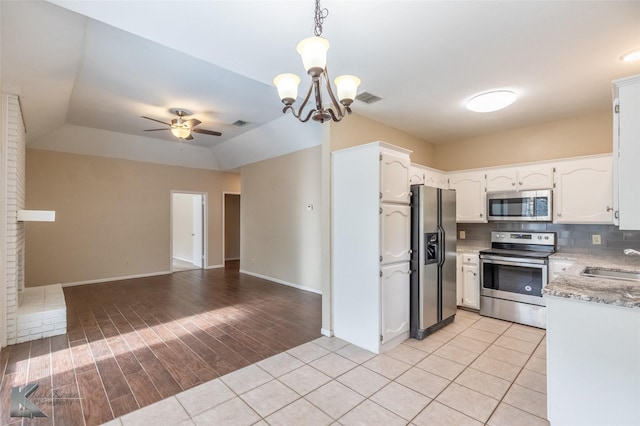 kitchen with ceiling fan with notable chandelier, stainless steel appliances, a sink, and white cabinetry