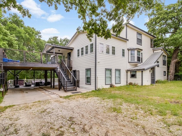 back of property featuring a deck, stairs, a patio area, concrete driveway, and a carport