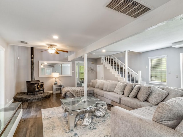 living area featuring visible vents, a wood stove, stairs, and wood finished floors