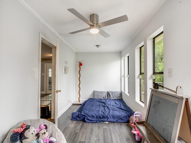bedroom featuring crown molding, a ceiling fan, visible vents, and wood finished floors