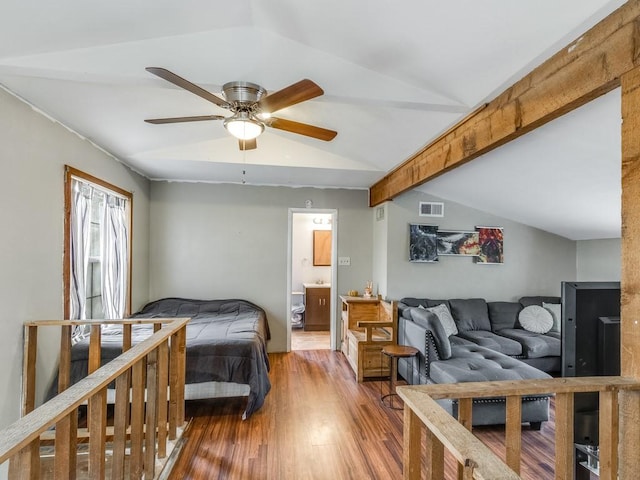 bedroom with visible vents, lofted ceiling, wood finished floors, connected bathroom, and a ceiling fan