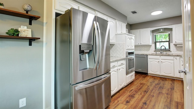 kitchen featuring visible vents, white cabinets, tasteful backsplash, a sink, and appliances with stainless steel finishes