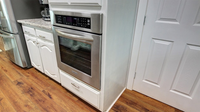 kitchen featuring white cabinetry, appliances with stainless steel finishes, and wood finished floors