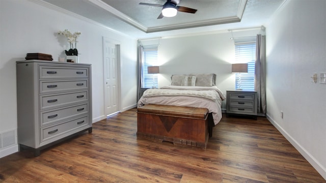 bedroom with ornamental molding, a raised ceiling, dark wood-style floors, and multiple windows