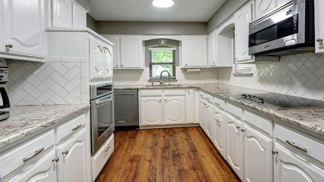 kitchen featuring a sink, appliances with stainless steel finishes, white cabinets, and tasteful backsplash