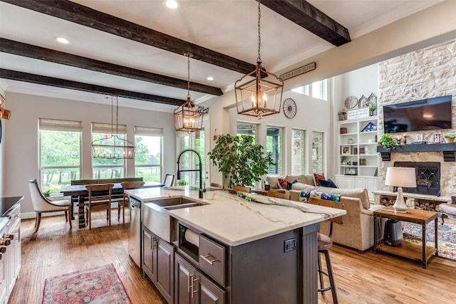 kitchen featuring beamed ceiling, light wood-style floors, open floor plan, a sink, and dishwasher