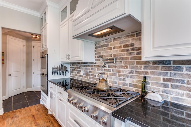 kitchen featuring stainless steel appliances, white cabinetry, ornamental molding, and glass insert cabinets