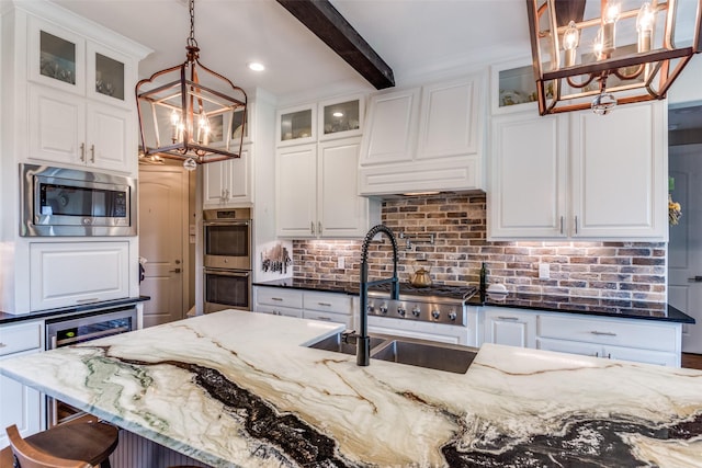 kitchen featuring an inviting chandelier, a sink, dark stone countertops, and appliances with stainless steel finishes