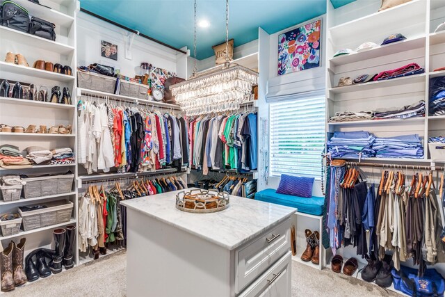 spacious closet featuring an inviting chandelier and carpet
