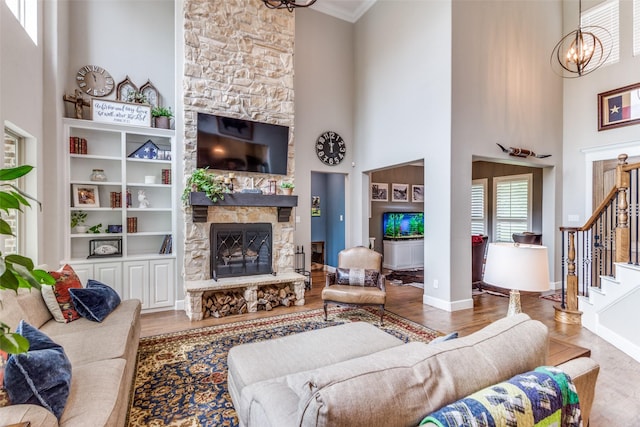 living area featuring an inviting chandelier, a high ceiling, a fireplace, and wood finished floors