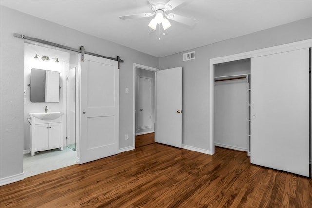 414 Jolee St, Richardson, TX 75080 - unfurnished bedroom featuring visible vents, a barn door, wood finished floors, a sink, and a closet