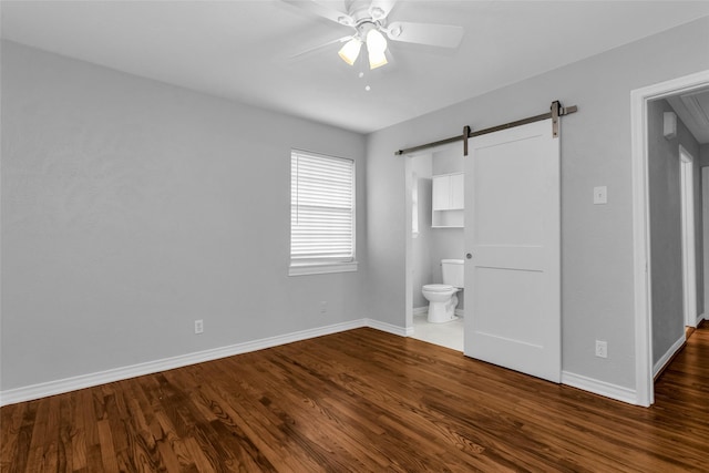 414 Jolee St, Richardson, TX 75080 - unfurnished bedroom featuring baseboards, dark wood-style floors, and a barn door