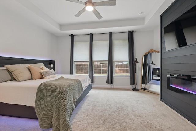bedroom featuring a raised ceiling, ceiling fan, and light carpet