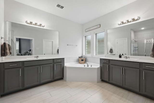 full bath featuring visible vents, a sink, a stall shower, and two vanities