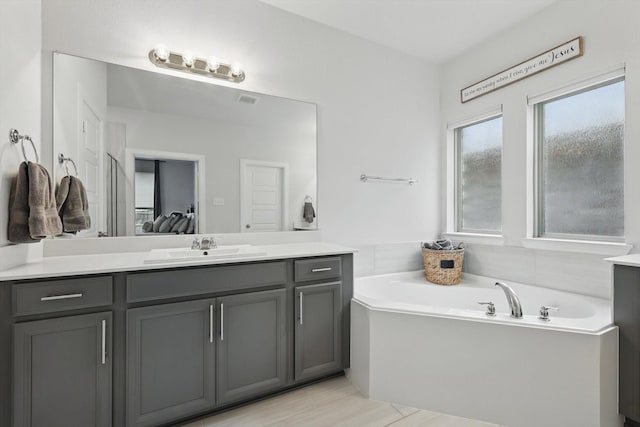 full bathroom featuring vanity, a garden tub, and visible vents