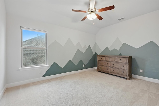 unfurnished bedroom featuring visible vents, lofted ceiling, baseboards, light colored carpet, and a ceiling fan
