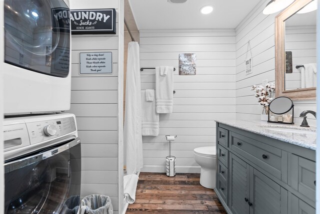 bathroom with stacked washer / drying machine, tiled shower, and wood finished floors