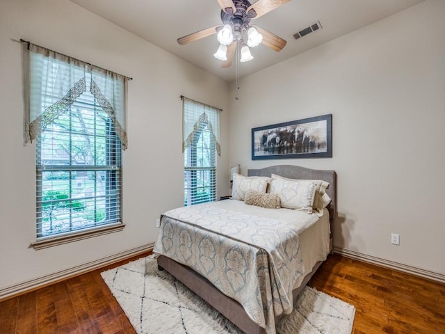 bedroom with visible vents, multiple windows, and wood finished floors
