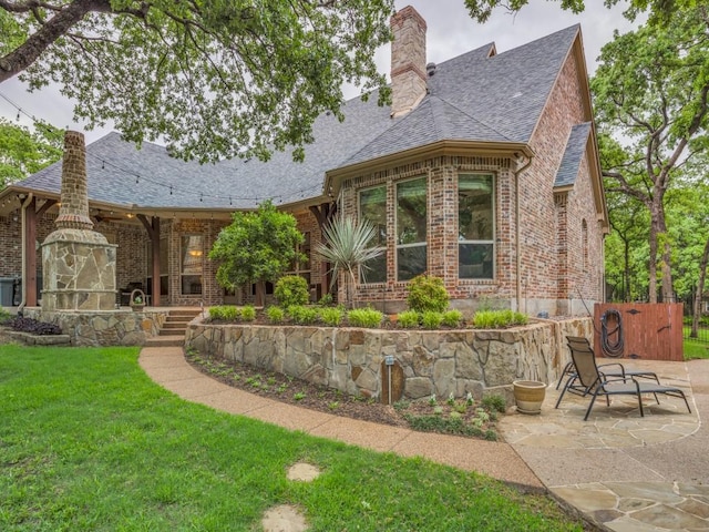 back of property featuring a lawn, brick siding, and a chimney