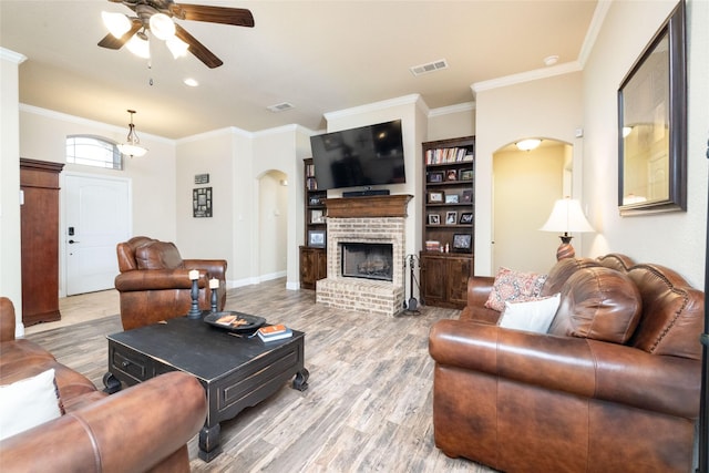 living area with arched walkways, ceiling fan, wood finished floors, and ornamental molding
