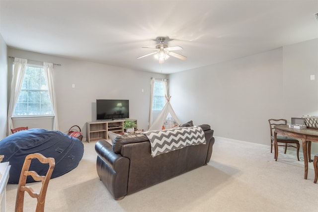 living area with visible vents, ceiling fan, a healthy amount of sunlight, and light carpet