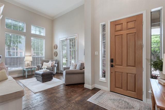 entryway with crown molding, baseboards, plenty of natural light, and a towering ceiling