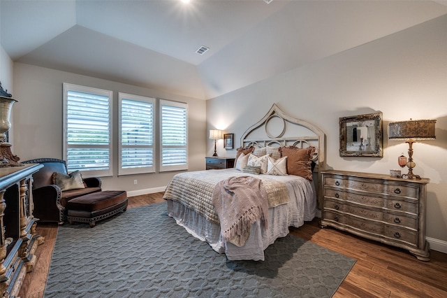 bedroom with baseboards, lofted ceiling, wood finished floors, and visible vents
