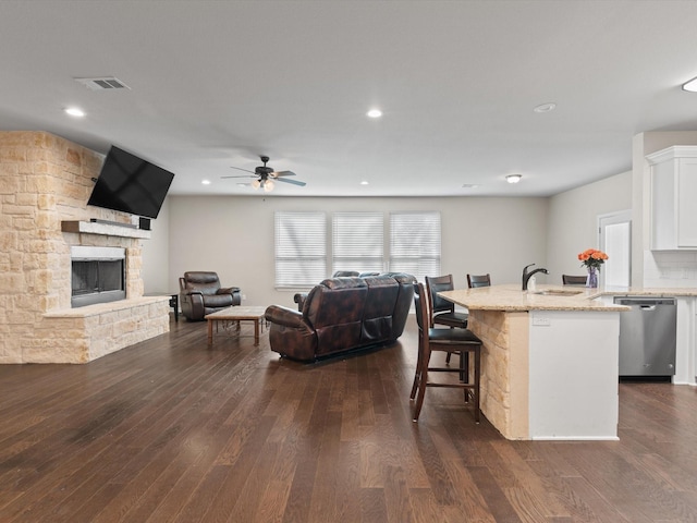 kitchen with stainless steel dishwasher, open floor plan, dark wood-type flooring, white cabinetry, and a sink